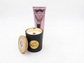 A black soy scented candle jar with a gold circular label reading 'Madagascar Vanilla' and a bamboo lid leaning beside it, shown next to avgerinos baby talc body cream tube gift set of gzen candles on a clean white background.Gzen Candles gift set with avgerinos cosmetics base in Cyprus ship worldwide. Buy online from Limassol.