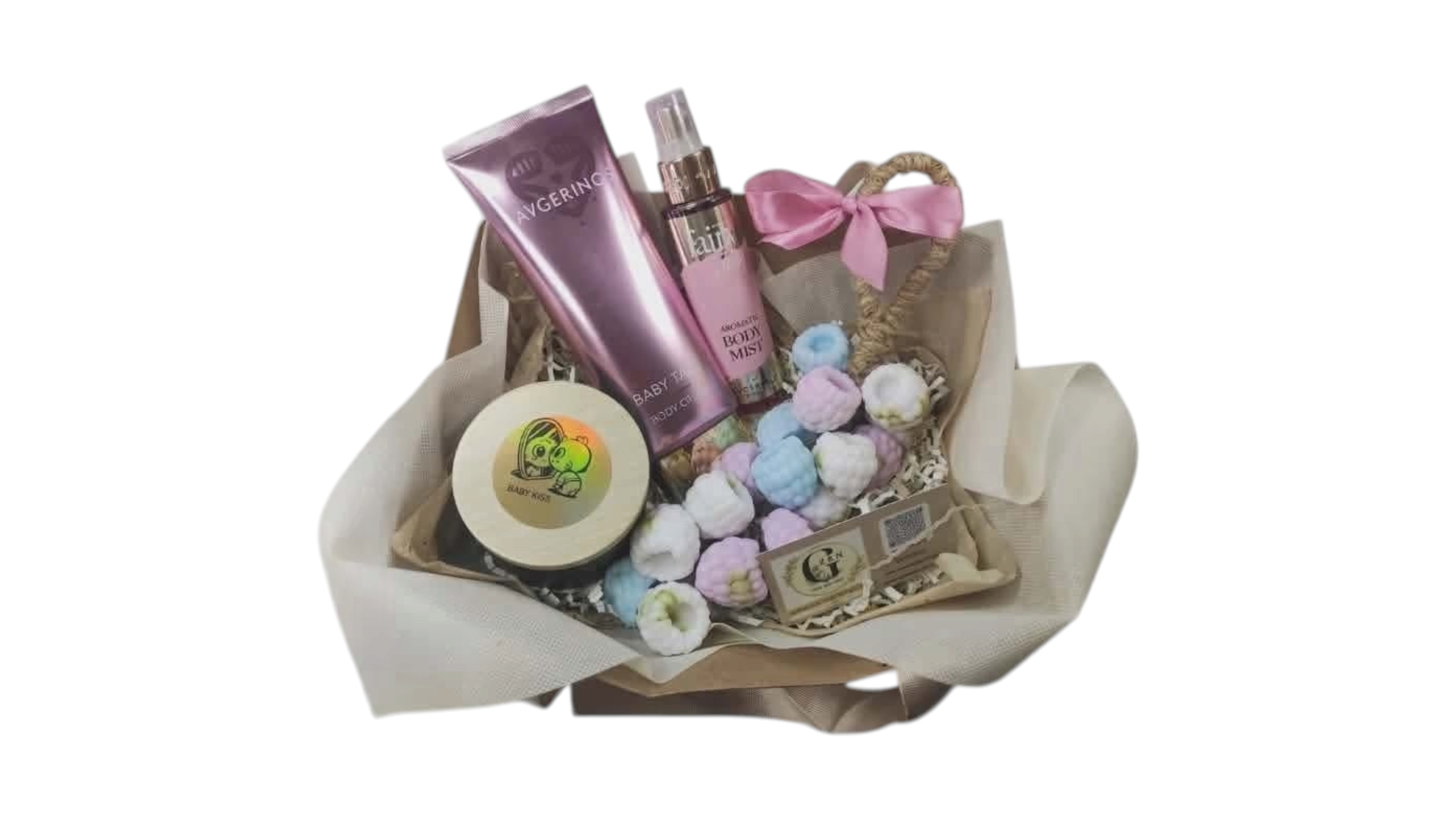 A gift basket filled with assorted bath and body items, including a pink tube, a pink spray bottle, a round tin, and pastel grape soap wrapped in beige tissue paper with a pink ribbon bow, on a white background. A small Gzen candle with wood wick and fairy dust mist by Avgerinos Cosmetics. 