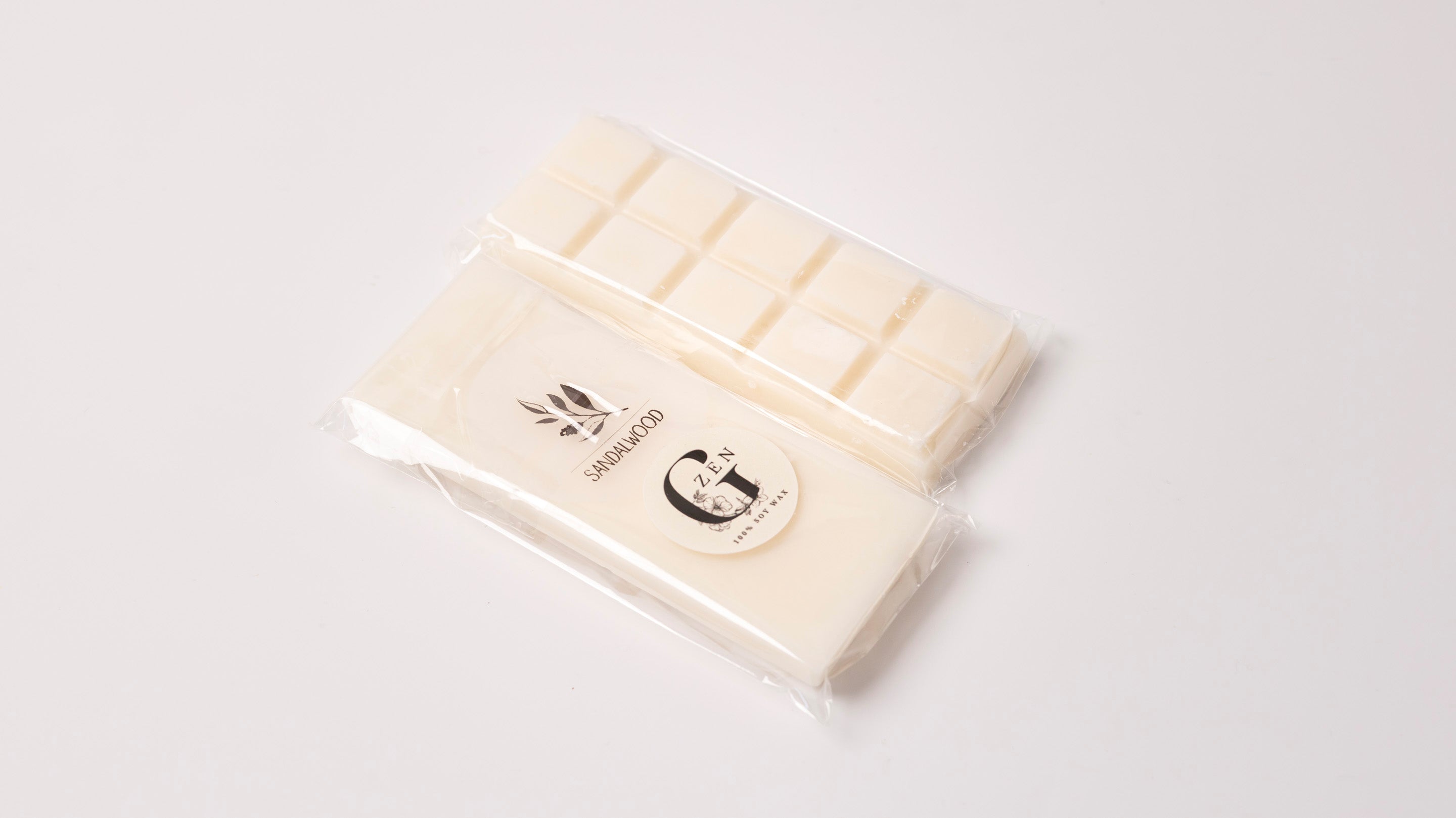 White chocolate soy scented wax melt bar with a gzen candle logo on a light gray background, scent sandalwood.