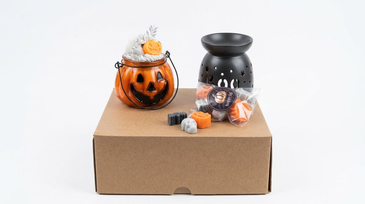 Halloween-themed candle gift set displayed on a brown cardboard box against a white background, featuring an orange jack-o'-lantern candle bucket, a black wax warmer, and small orange and gray candles, wax melts handmade by gzen candles based in Cyprus

