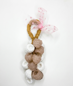A berries handmade soap on a robe ,or decorative hanging ornament featuring a gold braided loop, white and beige textured donut-shaped charms, and a pink polka-dot tulle ribbon bow, shown on a plain white background.