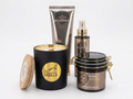 A set of four AVGERINOS cosmetics self-care products including a gzen soy scented candle in a black jar with a wooden wick, a body lotion tube of Perla avgerinos ,a body oil spray Perla bottle, and a body Perla scrub jar of avgerinos cosmetics,arranged on a white background. Perfect gift for her from Gzen gift box base in Limassol, Cyprus ship worldwide.