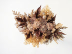 A decorative floral arrangement featuring faux succulent flowers in muted pink and beige tones, mixed with glittery bronze-brown leaves, gold glitter pinecones, and delicate beige filler stems on a plain white background.