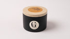 Black metal container with lid featuring a logo of gzen candles on a white background