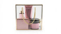 A three-piece baby talc scent gift set by Avgerinos Cosmetics in a clear acrylic box with a gold frame. The set includes a pink perfume bottle, a pink lotion tube, and a pink jar with a gold lid body oil, arranged together with a gold rope handle.