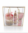 A luxury gift set in a clear acrylic box with a gold frame and rope handles, containing a fairy dust product by avgerinos cosmetics and a whipped desert candle soy on a white background.