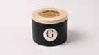 Black metal container with lid featuring a logo of gzen candles on a white background