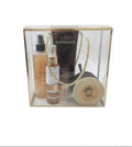 A clear acrylic gift box with a gold-toned lid and rope handle, containing several Aygerinos skincare and body care items including a dark brown tube, a spray bottle coco mist ,a coconut soy candle , set against a plain white background.