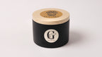 Black metal container with lid featuring a logo of gzen candles on a white background