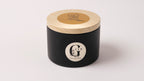 a scented soy candle handured in cyprus in a black metal tin with wood wick scent fresh & clean 