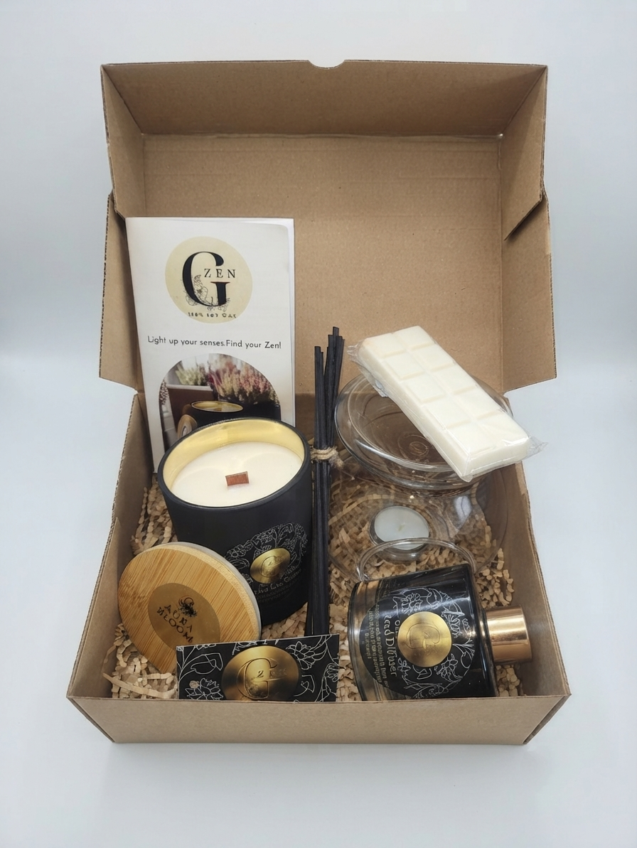 A curated gift box set from The Art of Scents, displayed inside an open brown cardboard box filled with shredded paper. The set includes a black soy candle with a gold wax core, a white chocolate bar, a reed diffuser stick bundle, a small decorative tin, a card, and a glass dish.