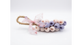 A handmade soap designed to look like a bunch of grapes (berries), featuring light pink and lavender crocheted berries on a tan jute-wrapped stem, adorned with a sheer pink floral ribbon bow, set against a plain white background. Χειροποίητο σαπούνι σε σχήμα σταφύλι Gzen Candles – Αρωματικό δώρο Λεμεσός, Κύπρος