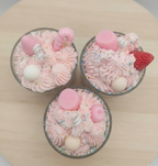 Three pink whipped aoy scented candles with decorative elements on a wooden surface