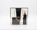 A three-piece  of Avgerinos skincare gift set in a clear acrylic box with a gold frame and rope handle. The set includes a black body cream my musk tube, a perfume musk, and a body musk oil bottle with a gold spray nozzle.