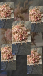 A dried flower arrangement in a round brown cardboard box, displayed on a white stool against a white background. The bouquet features light pink peony-like flowers, beige dried foliage, and small gold glitter accents.