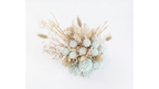 A dried floral arrangement featuring pale mint green artificial roses, beige pampas grass, and delicate white filler flowers, photographed from above on a plain white background.