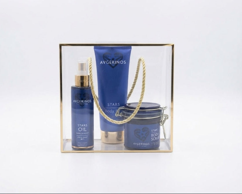 avgerinos cosmetics Star gift set for  in a clear acrylic box with a gold for woman e, containing a blue Star Oil bottle, a blue Star Body Wash tube, and a blue Star Body Butter jar with a gold rope handle, on a white background.