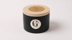 Black candle with wooden lid on a white background