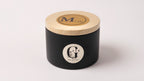 Black metal container with lid featuring a logo of gzen candles on a white background